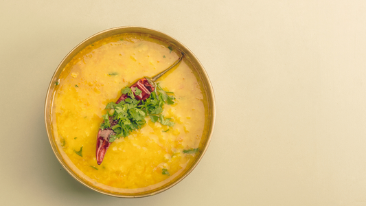 Bowl of moong dal khichdi with a red pepper on top and garnish