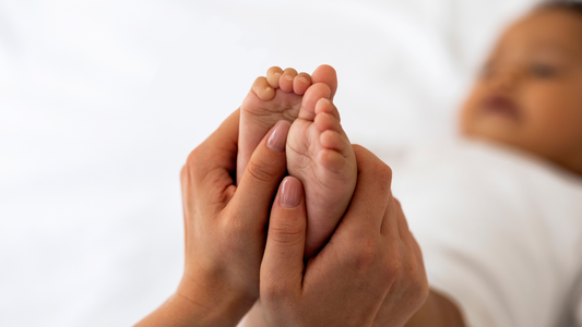 women holding baby feet in her hand with the baby blurred out in the back